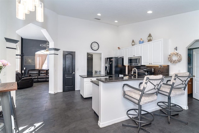 7376 Stetson Ln, Port Charlotte, FL 33981 - kitchen featuring freestanding refrigerator, stainless steel microwave, a towering ceiling, a peninsula, and dark countertops