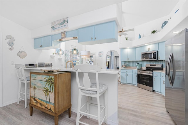 926 Boundary Blvd, Rotonda West, FL 33947 - kitchen with blue cabinets, appliances with stainless steel finishes, light wood-style floors, and decorative backsplash