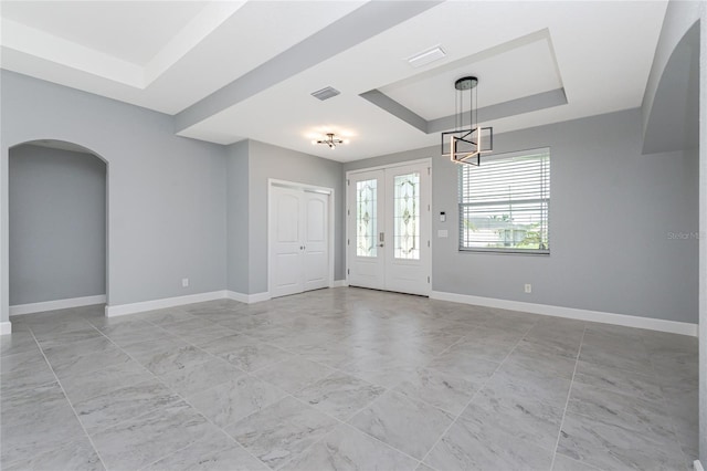 6 Medalist Ct, Rotonda West, FL 33947 - empty room featuring a tray ceiling, arched walkways, and a chandelier