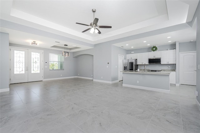 6 Medalist Ct, Rotonda West, FL 33947 - unfurnished living room with a tray ceiling, arched walkways, recessed lighting, a ceiling fan, and french doors