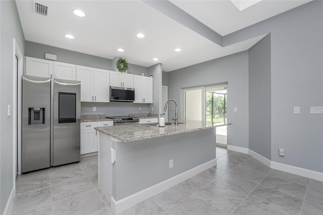 6 Medalist Ct, Rotonda West, FL 33947 - kitchen with stainless steel appliances, white cabinets, light stone counters, an island with sink, and light marble finish floors