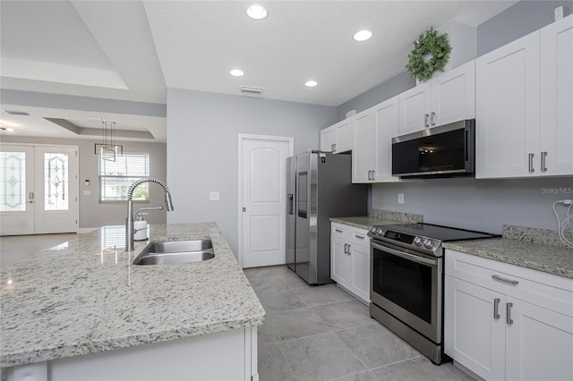 6 Medalist Ct, Rotonda West, FL 33947 - kitchen with appliances with stainless steel finishes, white cabinetry, recessed lighting, an island with sink, and light stone counters