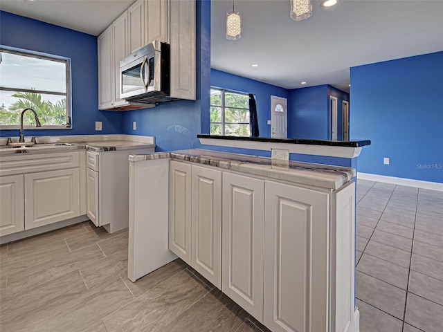 1295 S Maryknoll Rd, Englewood, FL 34223 - kitchen with stainless steel microwave, white cabinetry, recessed lighting, light countertops, and decorative light fixtures