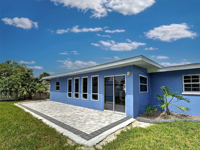 1295 S Maryknoll Rd, Englewood, FL 34223 - rear view of property featuring stucco siding, a patio, and a lawn