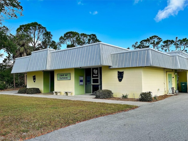 1295 S Maryknoll Rd, Englewood, FL 34223 - view of front of home featuring a metal roof, concrete block siding, and a front lawn