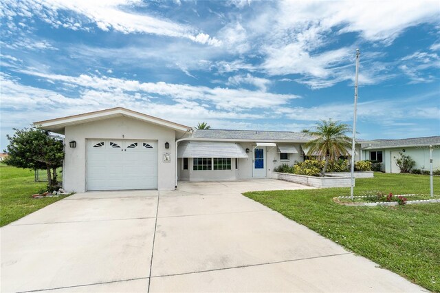 39 Caddy Rd, Rotonda West, FL 33947 - ranch-style home with a front lawn, stucco siding, an attached garage, and driveway