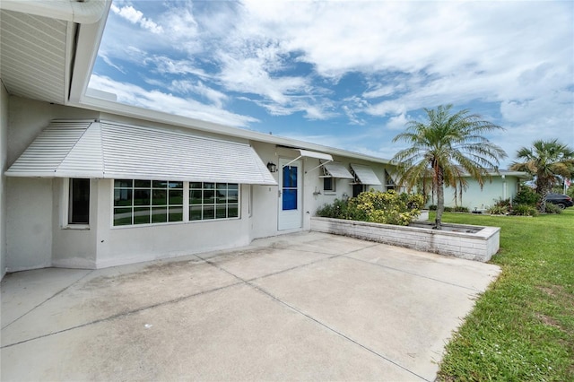 39 Caddy Rd, Rotonda West, FL 33947 - view of front facade with stucco siding, a patio area, and a front yard