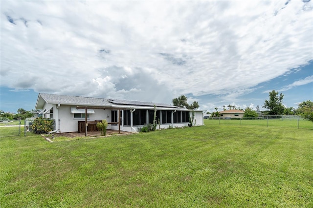 39 Caddy Rd, Rotonda West, FL 33947 - back of property featuring a fenced backyard, a sunroom, roof mounted solar panels, and stucco siding