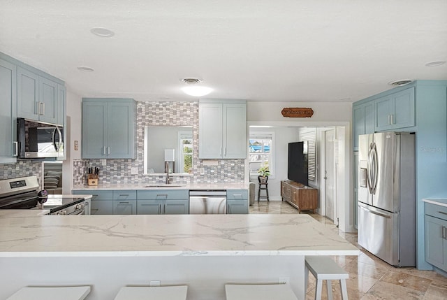 1030 Haste Ln, Englewood, FL 34223 - kitchen with appliances with stainless steel finishes, backsplash, a kitchen bar, and a peninsula