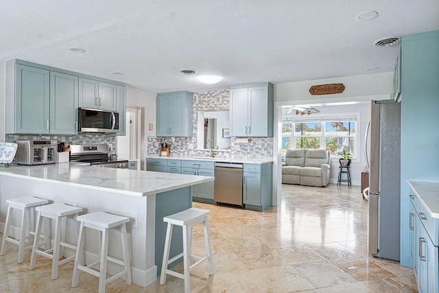 1030 Haste Ln, Englewood, FL 34223 - kitchen with stainless steel appliances, tasteful backsplash, a peninsula, a kitchen breakfast bar, and a textured ceiling