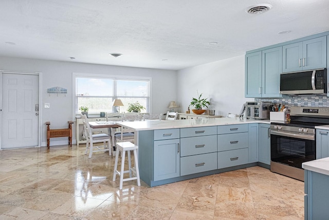 1030 Haste Ln, Englewood, FL 34223 - kitchen featuring stainless steel appliances, a peninsula, light countertops, decorative backsplash, and a breakfast bar