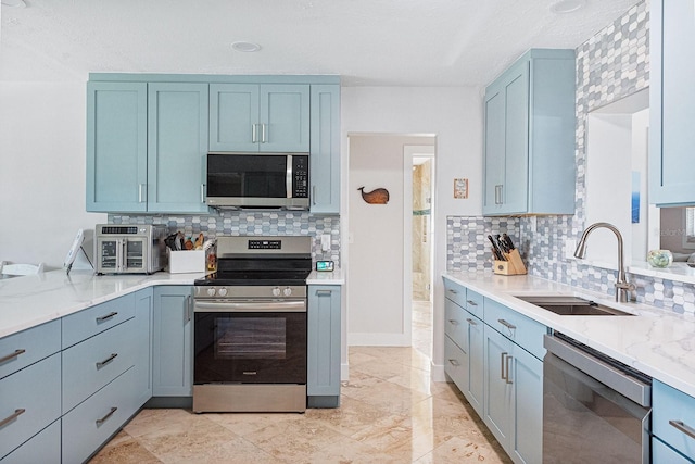 1030 Haste Ln, Englewood, FL 34223 - kitchen with stainless steel appliances, decorative backsplash, blue cabinets, and light stone countertops