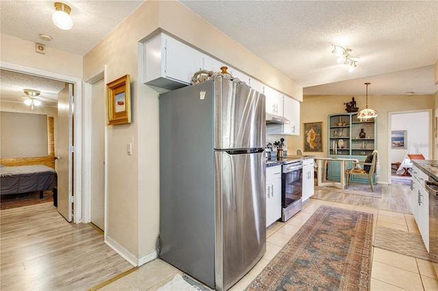 7104 Castilla St, Port Charlotte, FL 33981 - kitchen featuring appliances with stainless steel finishes, a textured ceiling, white cabinets, under cabinet range hood, and hanging light fixtures