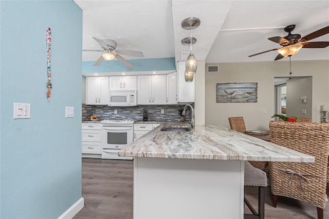 2955 N Beach Rd Unit A411, Englewood, FL 34223 - kitchen with a ceiling fan, white appliances, a peninsula, a kitchen bar, and light stone counters