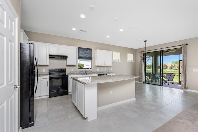 1530 Hyssop Loop, North Port, FL 34289 - kitchen with black appliances, a kitchen island, under cabinet range hood, white cabinets, and light stone counters