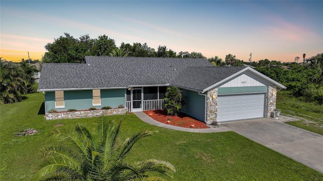7453 Spinnaker Blvd, Englewood, FL 34224 - ranch-style home with a yard, an attached garage, stone siding, and a shingled roof