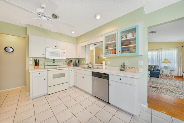 7453 Spinnaker Blvd, Englewood, FL 34224 - kitchen with white appliances, light countertops, light tile patterned flooring, a ceiling fan, and white cabinetry