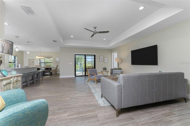 184 Spring Dr, Rotonda West, FL 33947 - living room with recessed lighting, a raised ceiling, light wood finished floors, a ceiling fan, and a chandelier