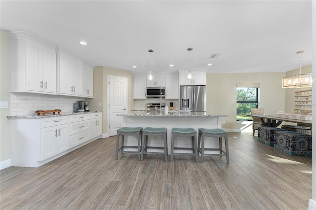 184 Spring Dr, Rotonda West, FL 33947 - kitchen featuring stainless steel appliances, light wood-type flooring, tasteful backsplash, white cabinets, and a chandelier
