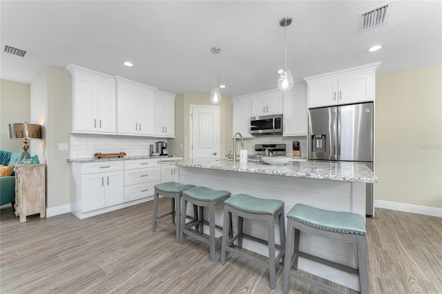 184 Spring Dr, Rotonda West, FL 33947 - kitchen with appliances with stainless steel finishes, light wood-style floors, backsplash, white cabinetry, and recessed lighting