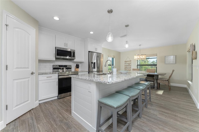 184 Spring Dr, Rotonda West, FL 33947 - kitchen with appliances with stainless steel finishes, light wood-style floors, a breakfast bar, white cabinets, and an island with sink