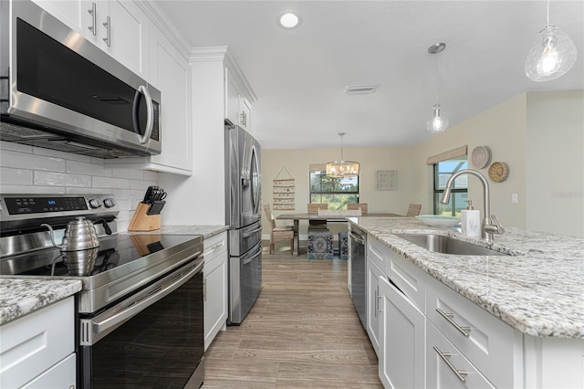 184 Spring Dr, Rotonda West, FL 33947 - kitchen with appliances with stainless steel finishes, a chandelier, light wood-style flooring, white cabinetry, and recessed lighting