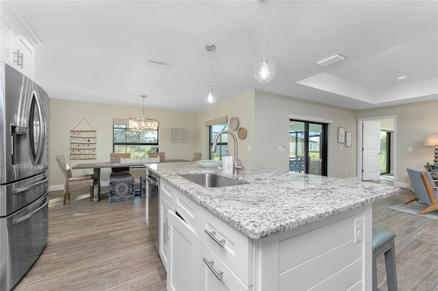 184 Spring Dr, Rotonda West, FL 33947 - kitchen featuring stainless steel appliances, a chandelier, light wood-style floors, white cabinets, and a kitchen island with sink