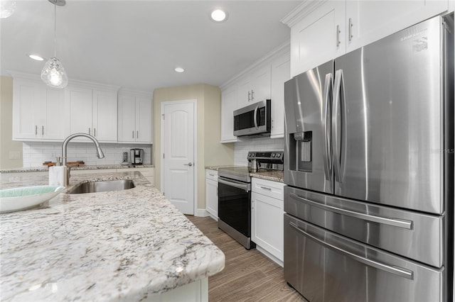 184 Spring Dr, Rotonda West, FL 33947 - kitchen featuring appliances with stainless steel finishes, white cabinetry, light wood-style flooring, decorative backsplash, and recessed lighting