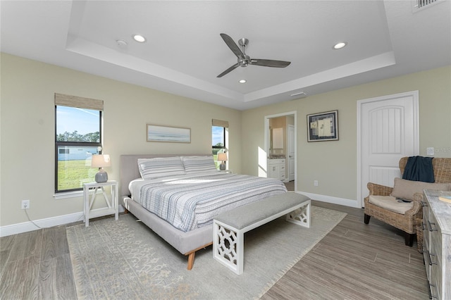 184 Spring Dr, Rotonda West, FL 33947 - bedroom featuring a tray ceiling, light wood-style flooring, recessed lighting, a ceiling fan, and ensuite bathroom