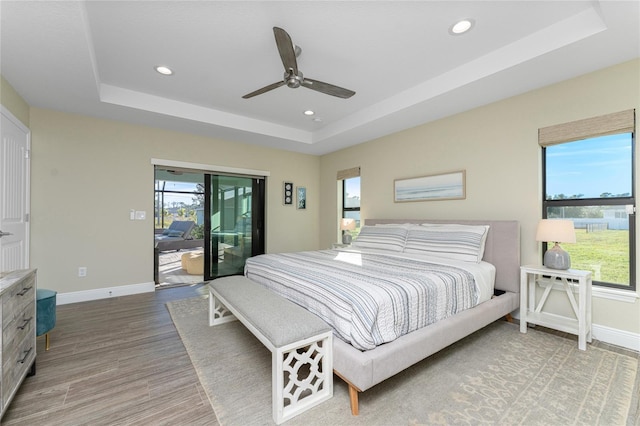 184 Spring Dr, Rotonda West, FL 33947 - bedroom featuring a tray ceiling, multiple windows, access to exterior, recessed lighting, and light wood-style floors