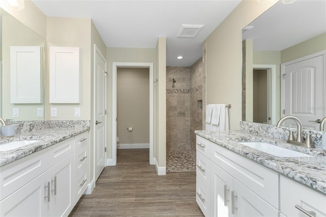 184 Spring Dr, Rotonda West, FL 33947 - bathroom featuring tiled shower, two vanities, and wood finished floors