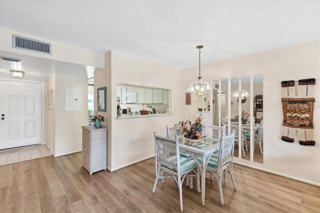 2004 Longpointe Cir Unit E2, Venice, FL 34293 - dining space featuring a chandelier, wood finished floors, a textured ceiling, and electric panel