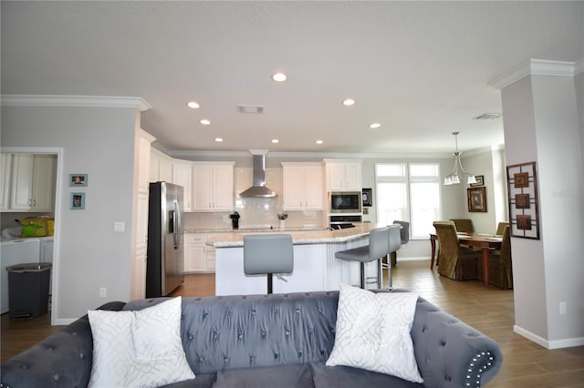 4354 Manatee Loop Unit 16A, Punta Gorda, FL 33950 - kitchen with stainless steel appliances, wall chimney exhaust hood, ornamental molding, separate washer and dryer, and open floor plan