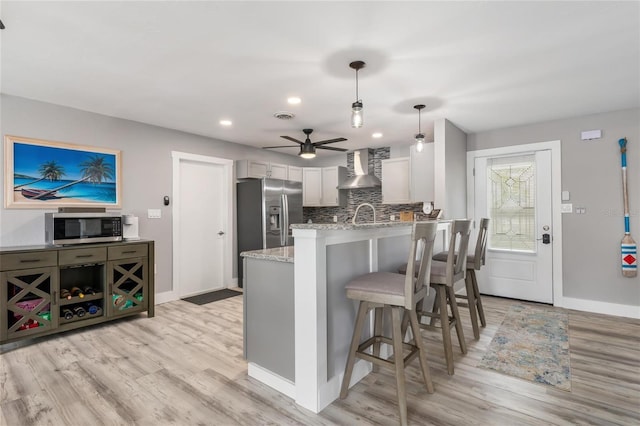 141 Baldwin Ct SE, Port Charlotte, FL 33952 - kitchen with stainless steel appliances, wall chimney range hood, a peninsula, light wood-style floors, and recessed lighting