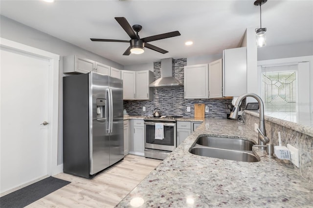 141 Baldwin Ct SE, Port Charlotte, FL 33952 - kitchen featuring appliances with stainless steel finishes, wall chimney range hood, a ceiling fan, backsplash, and light wood-type flooring