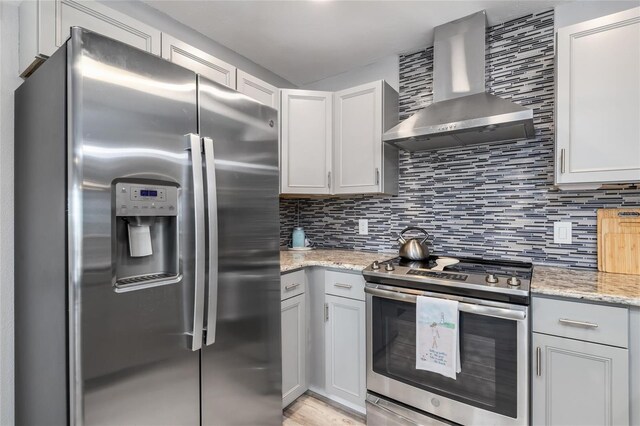 141 Baldwin Ct SE, Port Charlotte, FL 33952 - kitchen featuring stainless steel appliances, wall chimney exhaust hood, decorative backsplash, and light stone counters