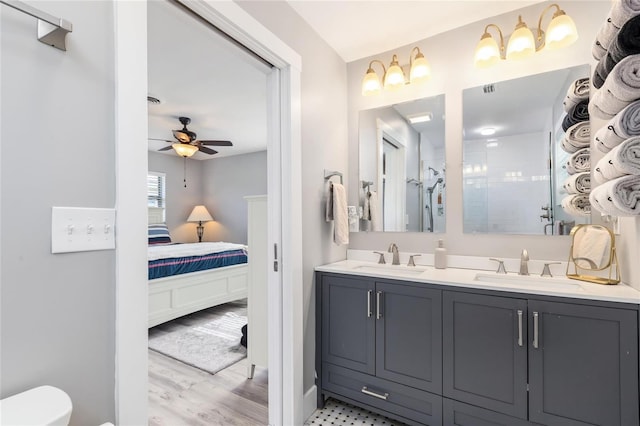 141 Baldwin Ct SE, Port Charlotte, FL 33952 - ensuite bathroom featuring double vanity, a ceiling fan, a tile shower, and wood finished floors