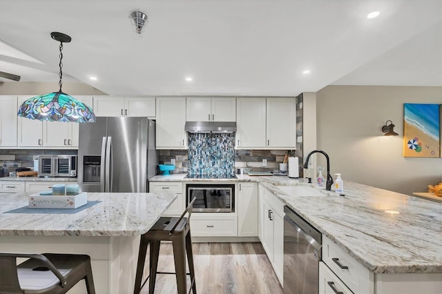 1401 S Mccall Rd Unit 205B, Englewood, FL 34223 - kitchen featuring appliances with stainless steel finishes, under cabinet range hood, a peninsula, light wood finished floors, and a breakfast bar area