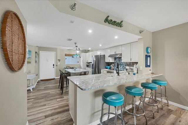 1401 S Mccall Rd Unit 205B, Englewood, FL 34223 - kitchen featuring under cabinet range hood, stainless steel fridge with ice dispenser, light wood-type flooring, a peninsula, and a center island