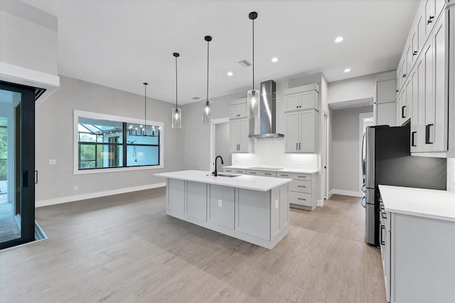 14089 Wenzel Ave, Port Charlotte, FL 33981 - kitchen featuring wall chimney exhaust hood, an island with sink, light wood-style floors, light countertops, and recessed lighting
