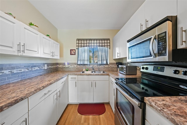 7580 Hanchey St, North Port, FL 34287 - kitchen with stainless steel appliances, light wood-style flooring, backsplash, and white cabinetry