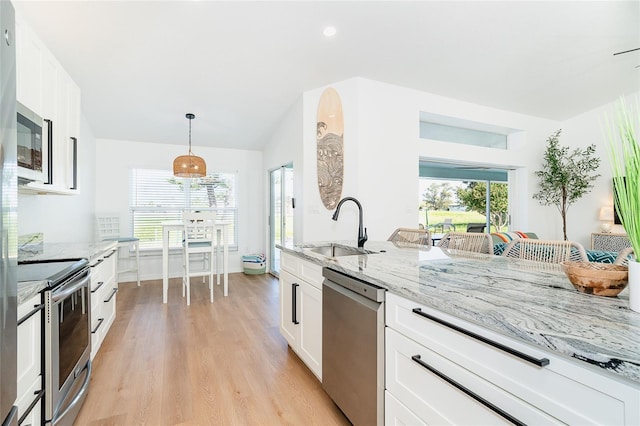 172 Mariner Ln, Rotonda West, FL 33947 - kitchen featuring appliances with stainless steel finishes, light stone counters, light wood-type flooring, white cabinetry, and hanging light fixtures
