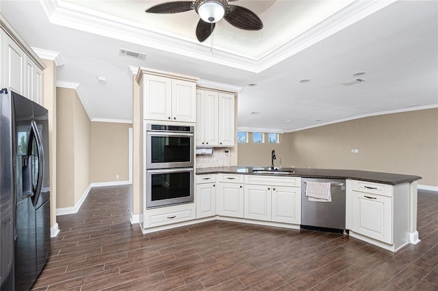 9150 Pine Cove Dr, Englewood, FL 34224 - kitchen featuring stainless steel appliances, a peninsula, ceiling fan, dark countertops, and crown molding