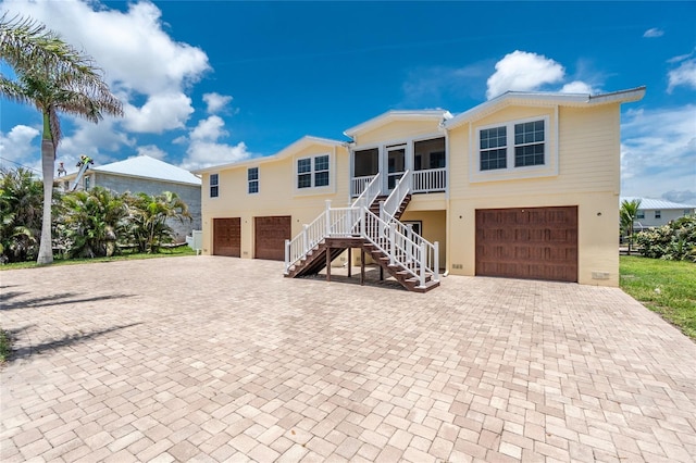 9150 Pine Cove Dr, Englewood, FL 34224 - raised beach house featuring a garage, stairway, decorative driveway, and a sunroom