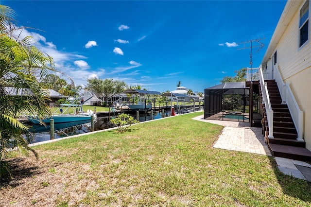 9150 Pine Cove Dr, Englewood, FL 34224 - view of green lawn with a dock, a patio area, a water view, boat lift, and glass enclosure