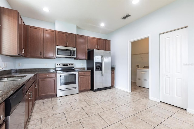 7318 61st St E, Palmetto, FL 34221 - kitchen featuring appliances with stainless steel finishes, washer / clothes dryer, light tile patterned floors, dark stone countertops, and recessed lighting