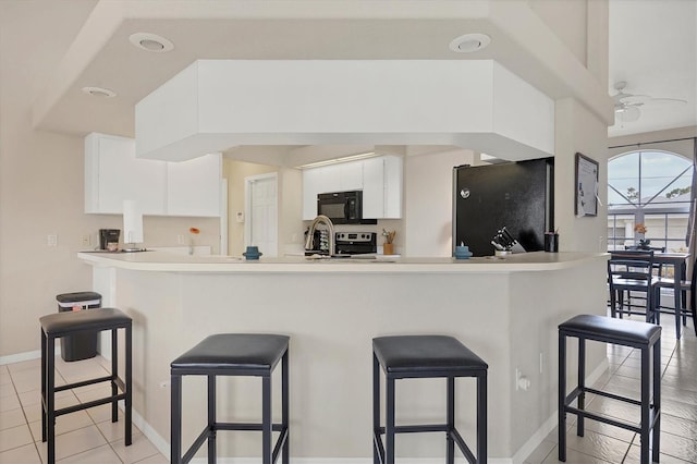 102 Marker Rd, Rotonda West, FL 33947 - kitchen with black microwave, freestanding refrigerator, white cabinets, and a breakfast bar area