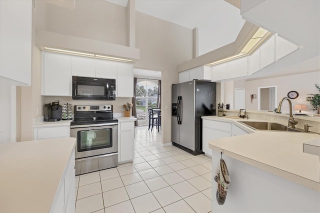 102 Marker Rd, Rotonda West, FL 33947 - kitchen with stainless steel appliances, light countertops, light tile patterned floors, white cabinetry, and a towering ceiling