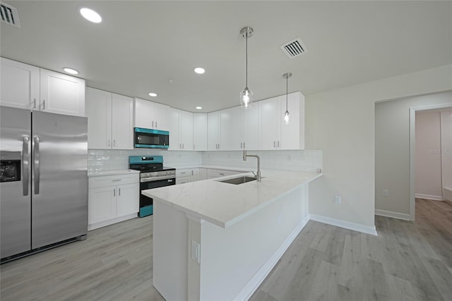 238 Boundary Blvd Unit 3, Rotonda West, FL 33947 - kitchen featuring appliances with stainless steel finishes, a peninsula, light wood finished floors, white cabinetry, and decorative backsplash