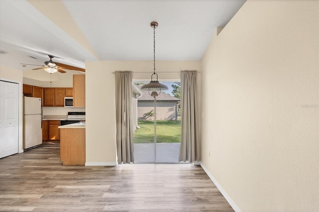 3768 Billingham Ln, North Port, FL 34288 - kitchen with electric stove, freestanding refrigerator, brown cabinets, light wood finished floors, and lofted ceiling